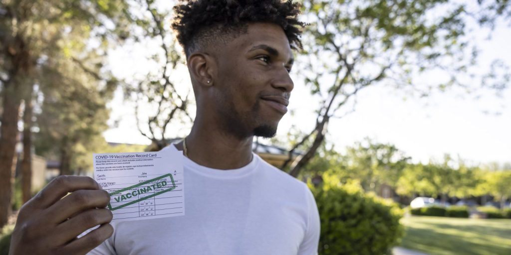 Man smiling holding a vaccination card